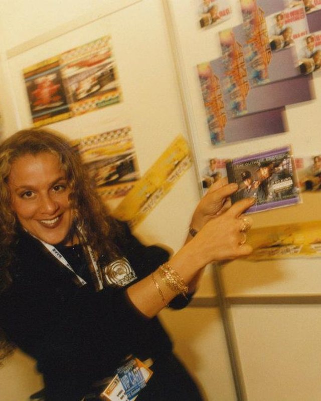 A smiling woman delegate pinning flyers to a wall at the first Amsterdam Dance Event in 1996
