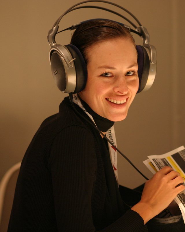 A smiling woman with studio headphones at an ADE Pro listening session